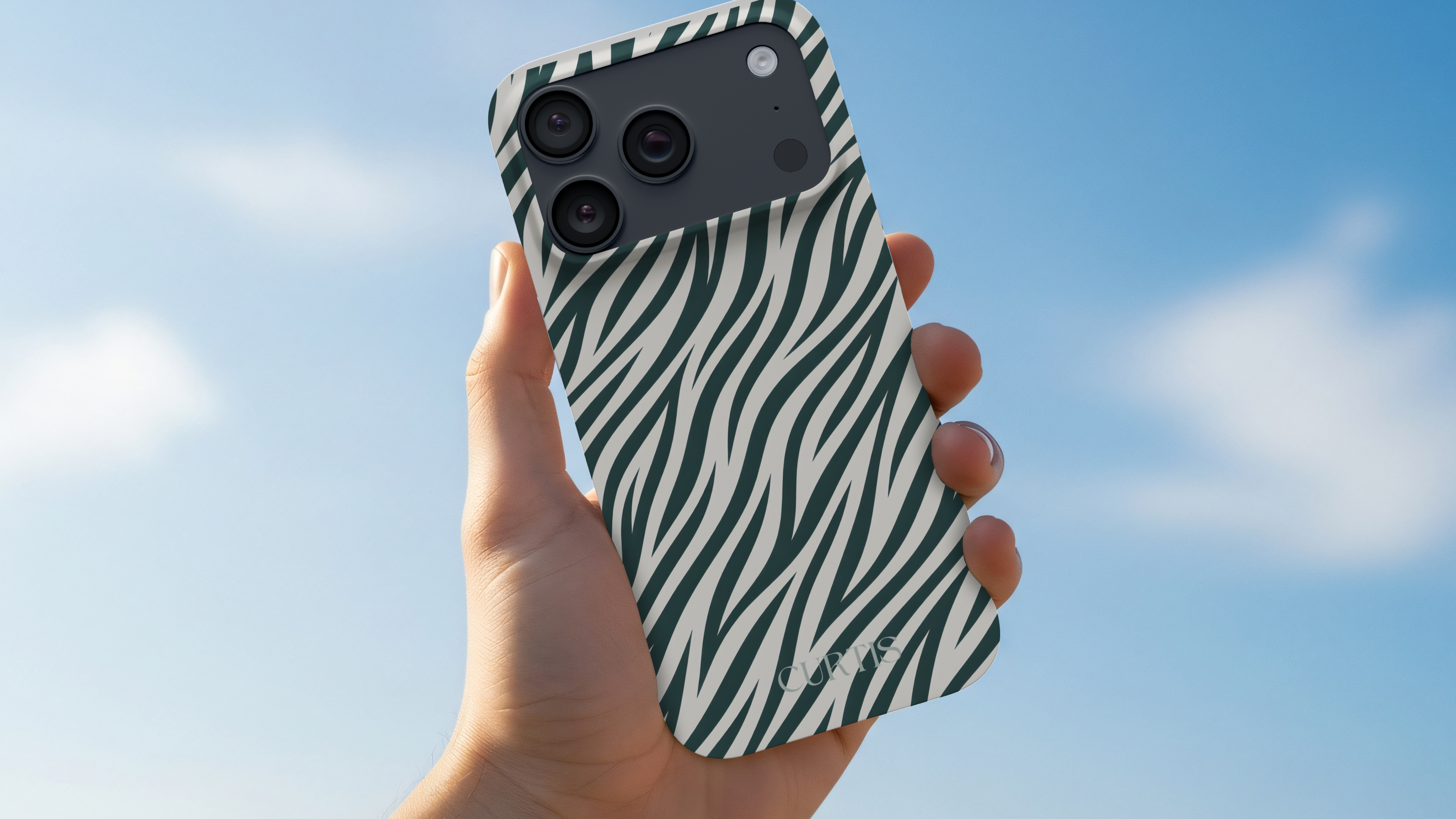 Hand holding a phone with a zebra pattern case against a blue sky.